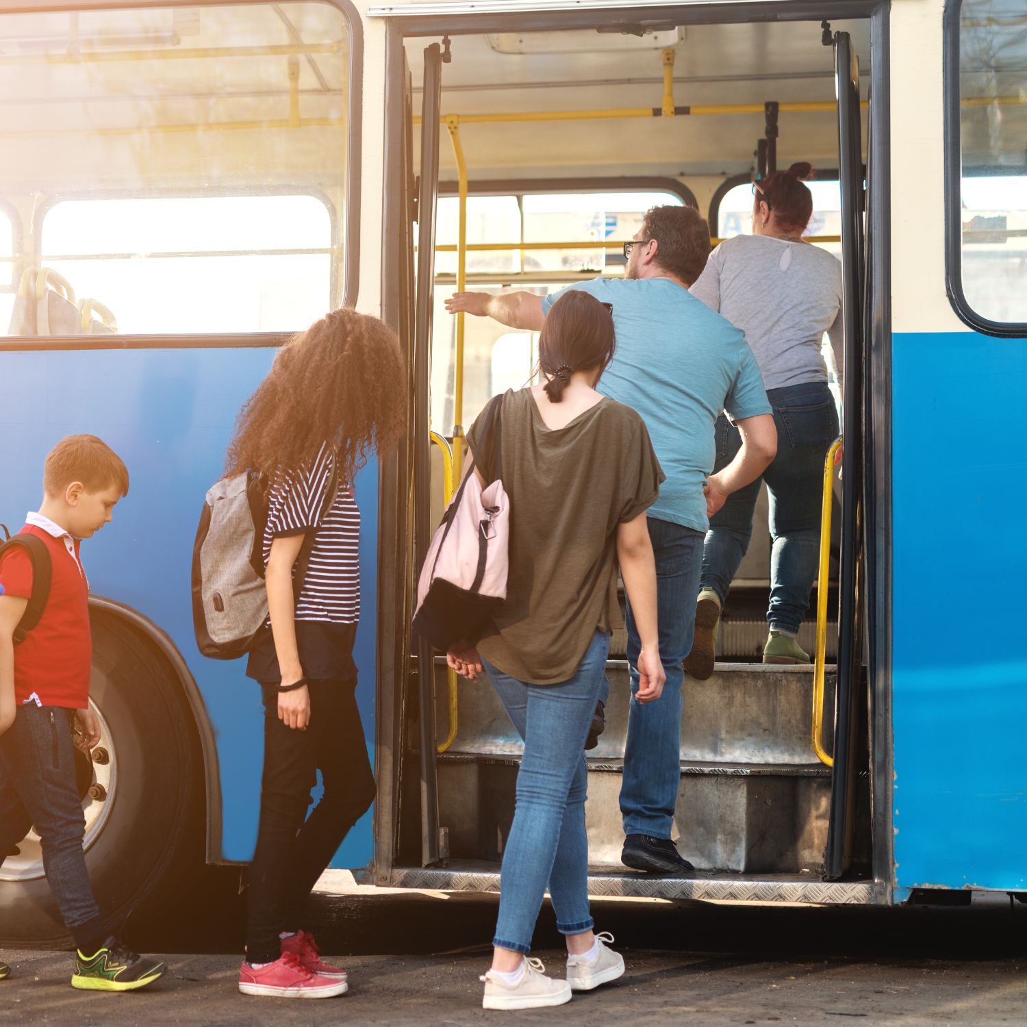 Group of people, including children and adults, boarding a blue bus.